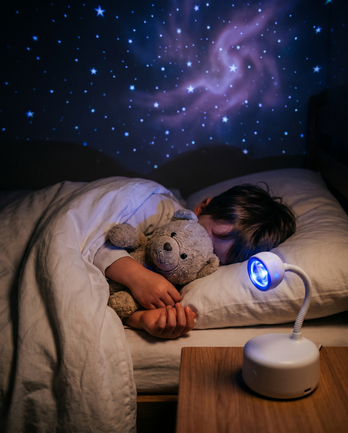 Child in bed looking up at stars projected on the ceiling